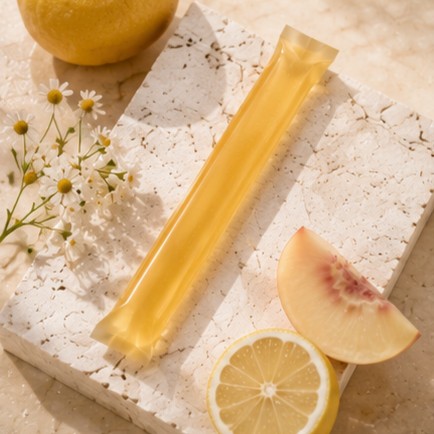 Daily jelly stick propped on a travertine slab with lemon and white peach