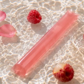 Glow jelly stick in rippling water with rose petals and raspberries