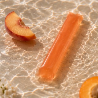 Move jelly stick leaning on stone with cubed mango and peach slice